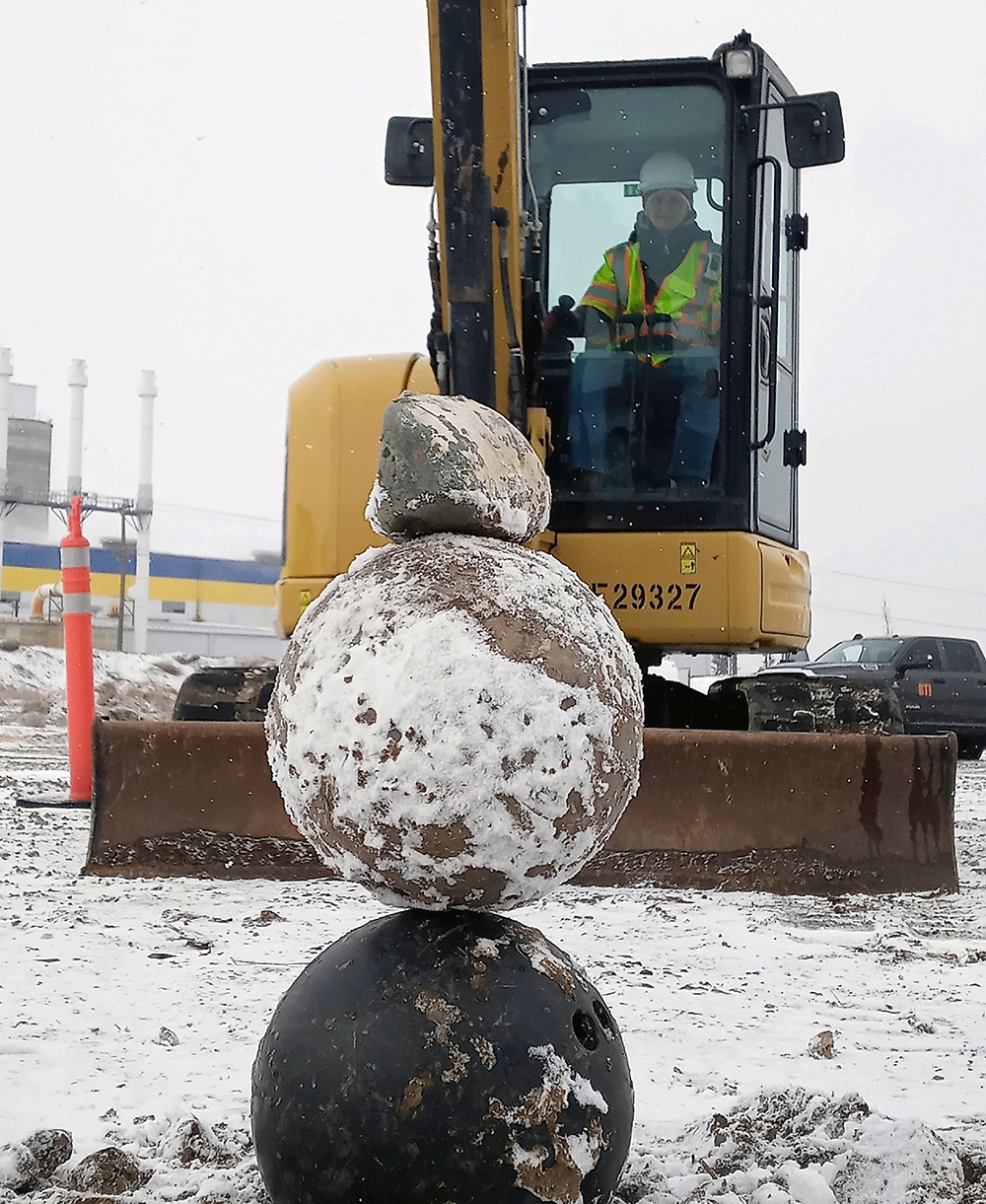 Worker in Idaho using a Catepillar for road work. Large rocks in the foreground.